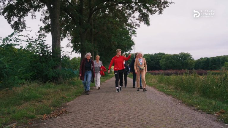 Buurtsportcoach wandelt met een groep senioren over een wandelpad in Rucphen